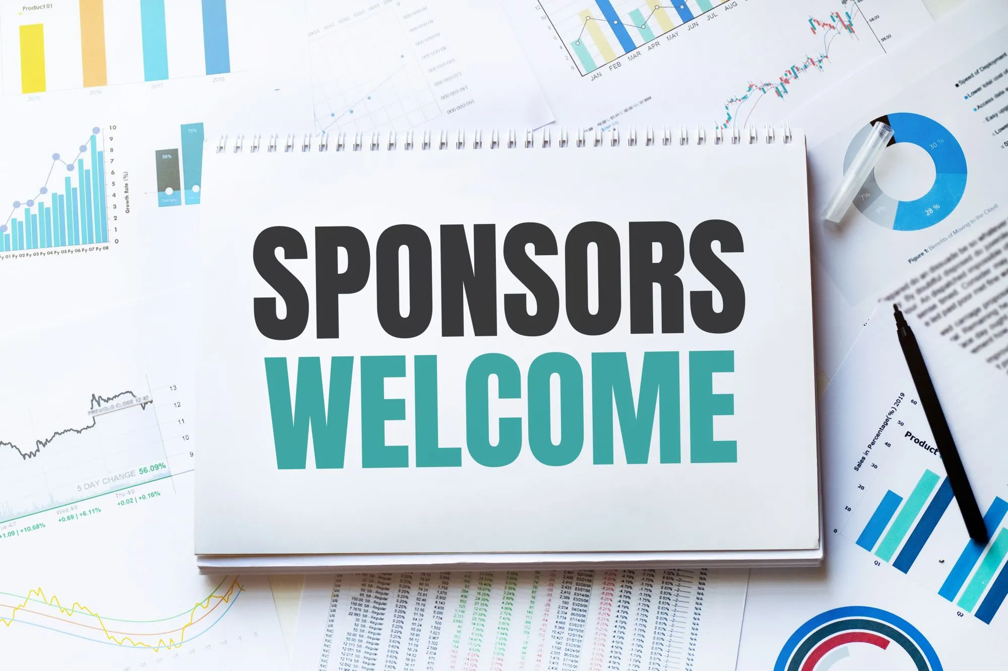 A notebook on a desk reading "Sponsors Welcome"